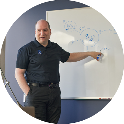  A man sitting in a chair in front of a whiteboard.<br />

