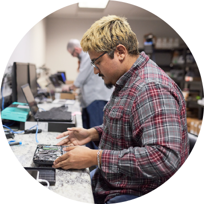 An IT tech working on a laptop at their workspace.<br />
